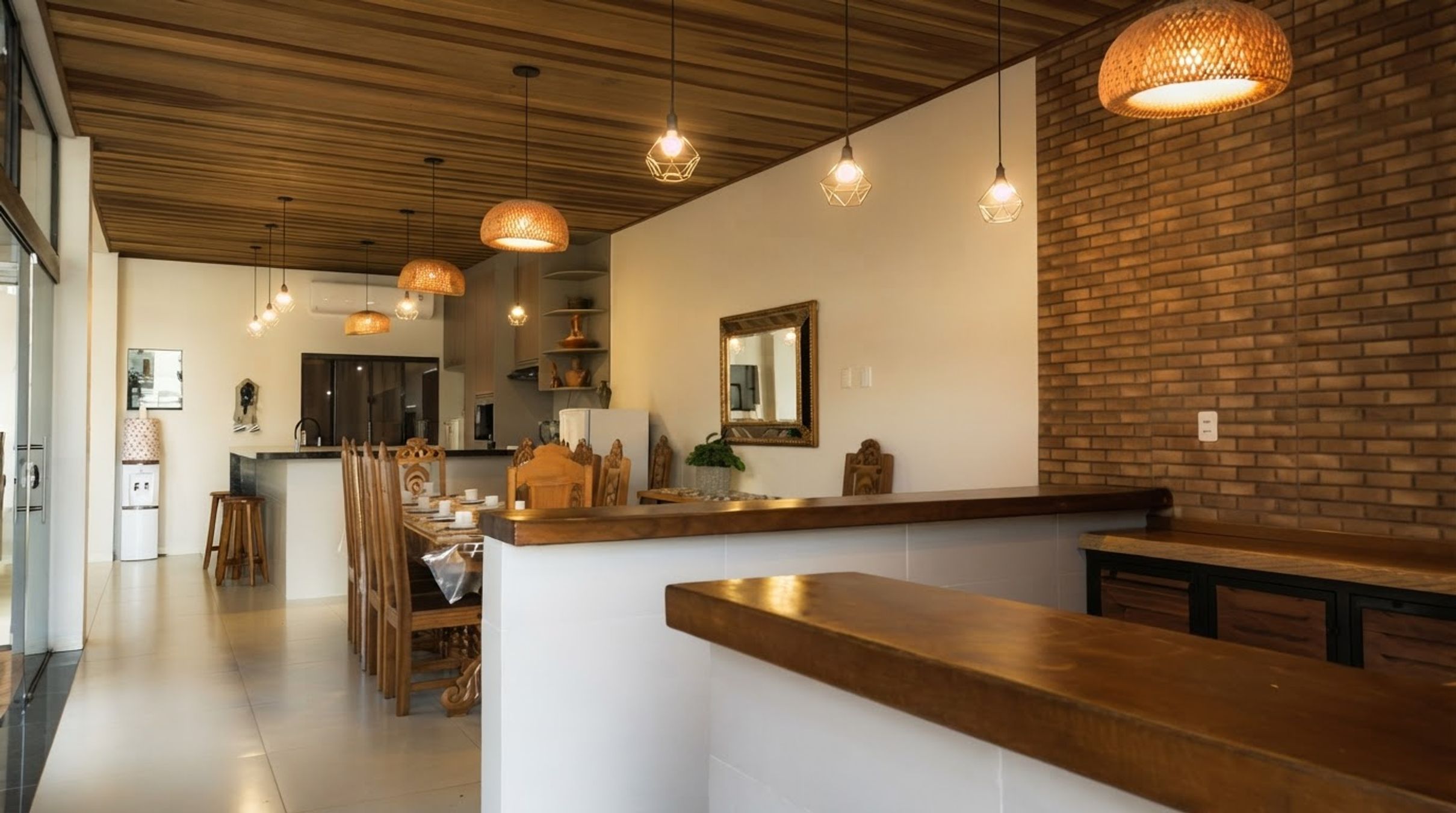 Cozinha moderna com bancadas de madeira, luminárias pendentes e parede de tijolos.