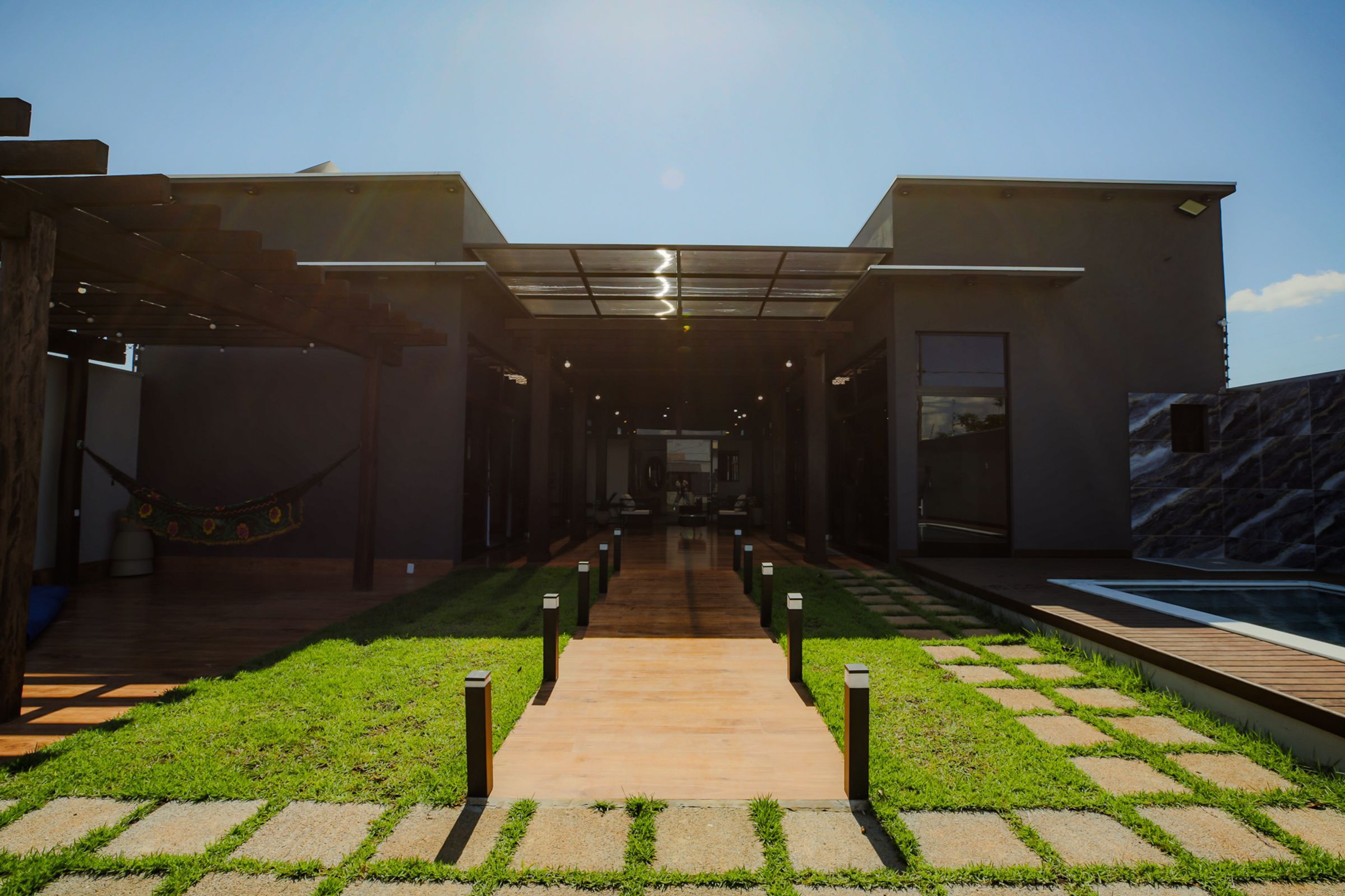 Um edifício moderno com um caminho central que leva a uma área de piscina.