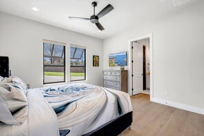 Ein Schlafzimmer mit Bett, Deckenventilator, Kommode und Fernseher.