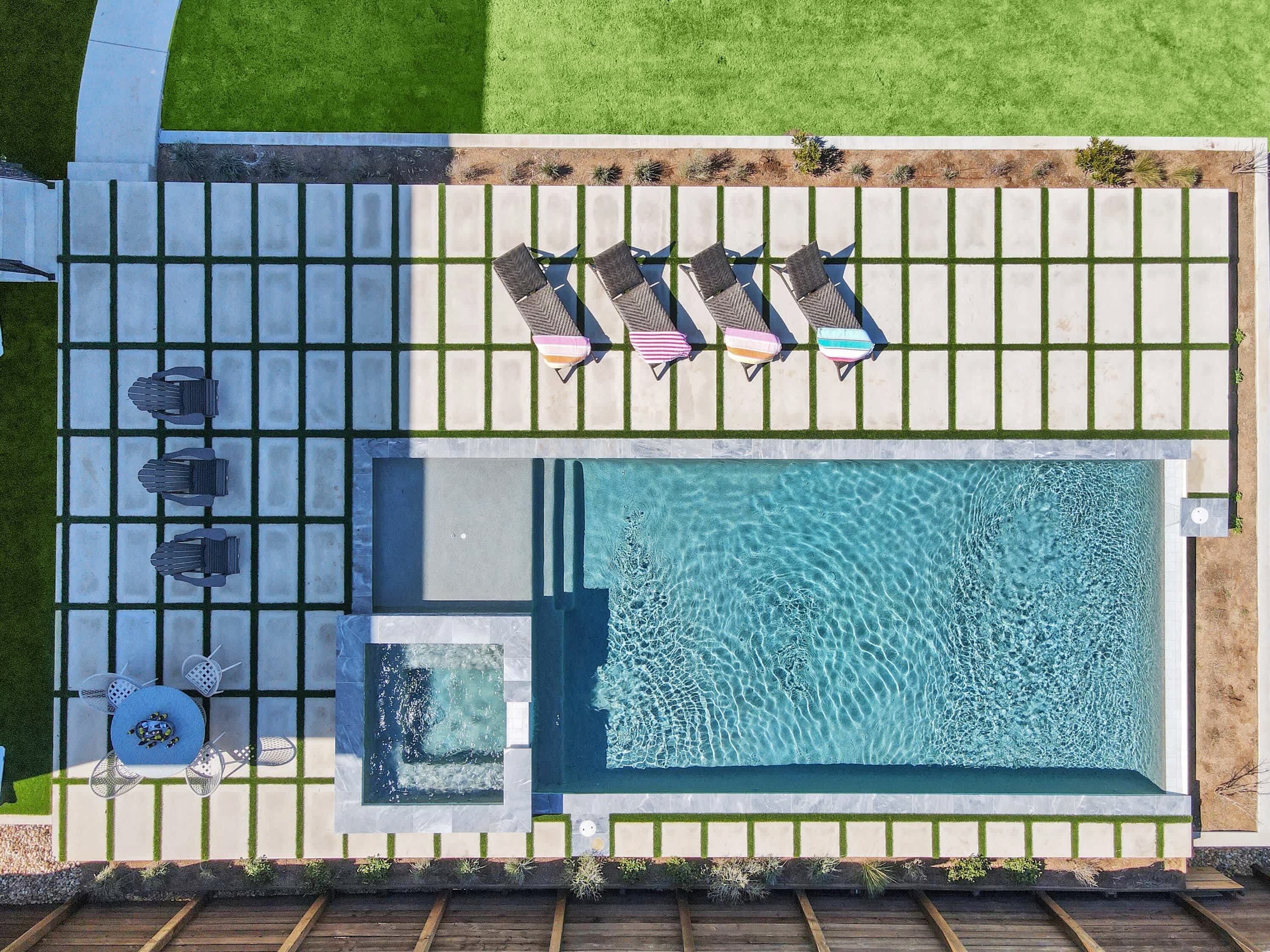 Vue aérienne d’un espace piscine comprenant un jacuzzi, des chaises longues et une petite terrasse.