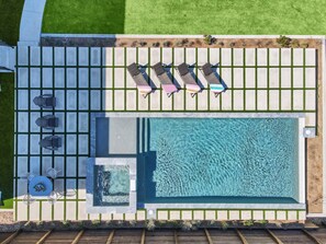 Ein Luftbild eines Poolbereichs mit Whirlpool, Liegestühlen und einer kleinen Terrasse.