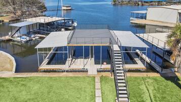 A marina with a glass-enclosed pool area, docked boats, and a clear view of the water.