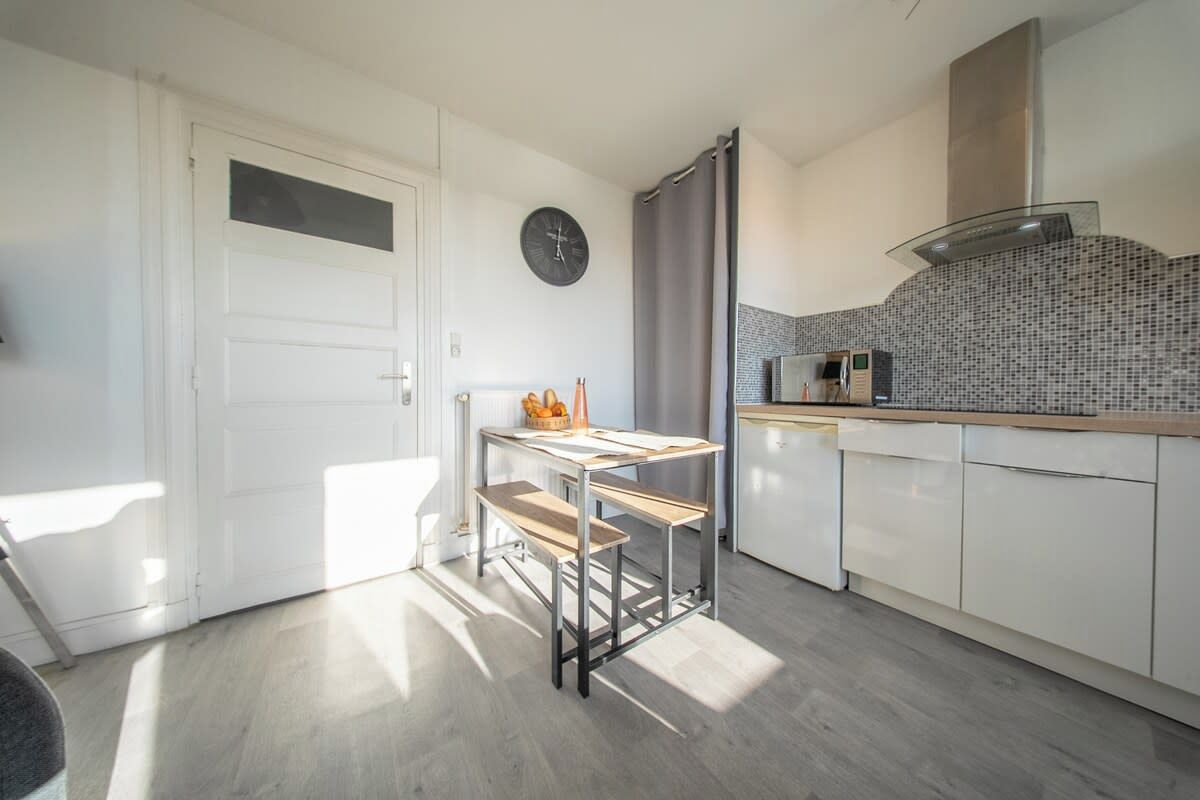 A modern kitchen with a white door, a clock, a kitchen island, and a microwave.