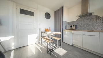 A modern kitchen with a white door, a clock, a kitchen island, and a microwave.