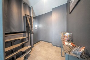 Una escalera con escalones de madera que conducen a una plataforma, un cuadro colgado en la pared y una mesa con revistas.