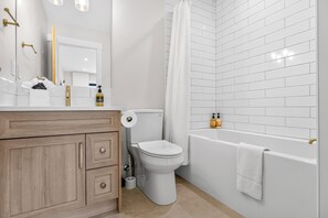 A modern bathroom with a toilet, sink, and bathtub.