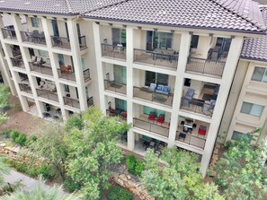 Un edificio residencial de varios pisos con balcones, mobiliario exterior y un jardín ajardinado.