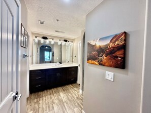 A bathroom with a large mirror, a sink, and a dark-colored cabinet. - Penthouse Paradise | Views, Pool & Hot Tub (St George)