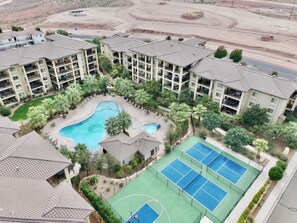 Un complejo residencial con varios edificios de apartamentos, piscina y cancha de tenis.