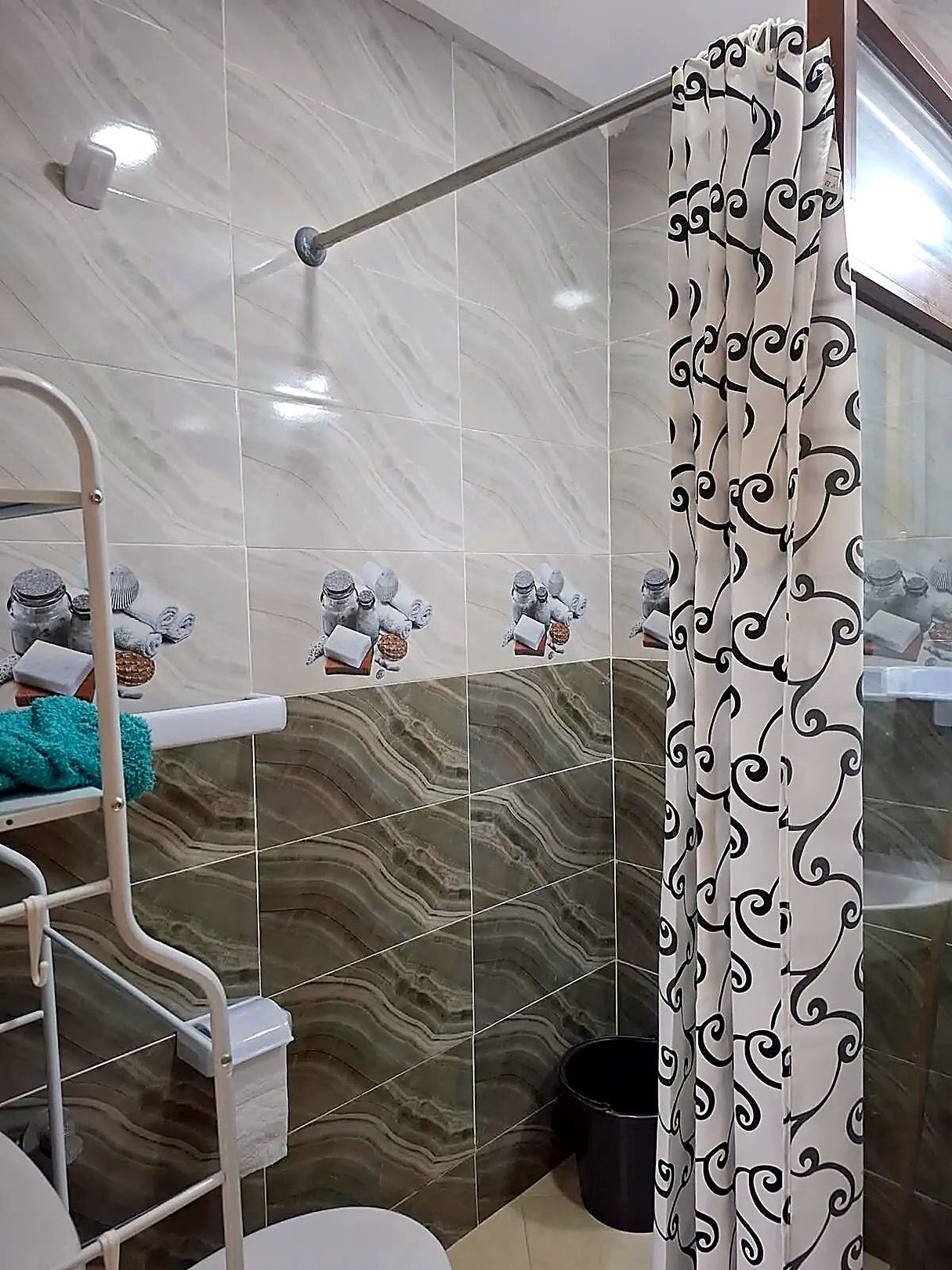 Une salle de bain avec un rideau de douche, un porte-serviettes et une étagère contenant des articles de toilette.