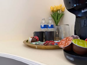Bandeja con alimentos, botellas de agua y un florero con flores amarillas sobre una encimera de hotel.
