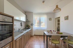 Une cuisine moderne avec un coin repas, une vue par la fenêtre et une table à manger dressée avec de la nourriture et des boissons.