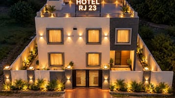 Un hotel moderno con techo plano, múltiples ventanas y un cartel que indica 'HOTEL RJ 23'.