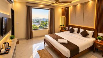 A hotel room with a large bed, a television, a desk with a coffee maker, and a view of the city.