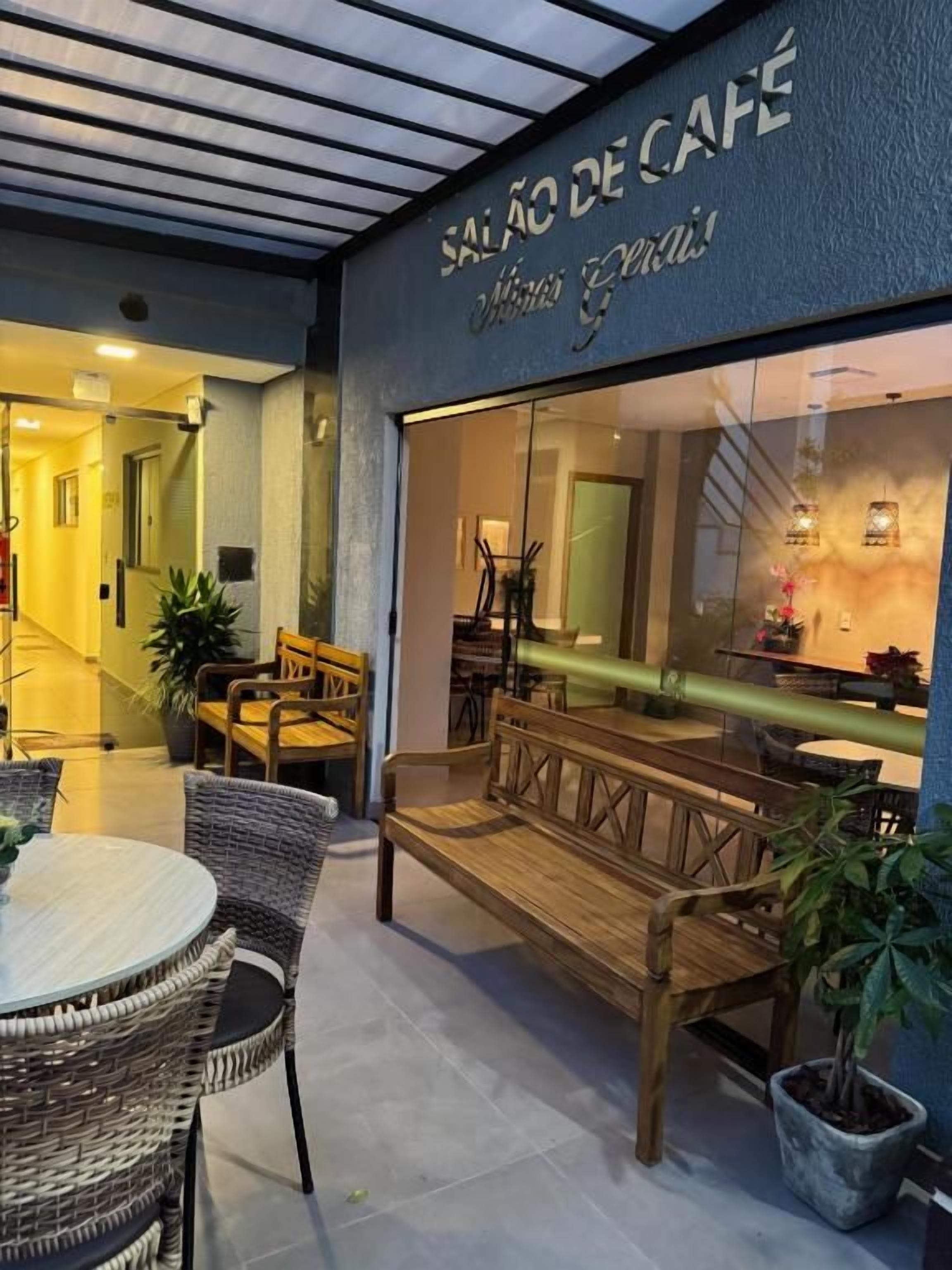 An outdoor seating area with wicker furniture and a glass wall of a café.