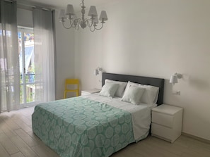 Une chambre à coucher avec un lit, des tables de chevet, un lustre et une vue par la fenêtre.