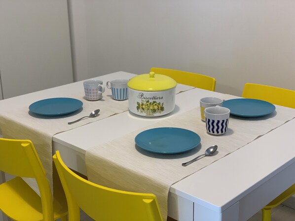 Una mesa con platos azules, un recipiente amarillo y blanco, y tazas con diseños.