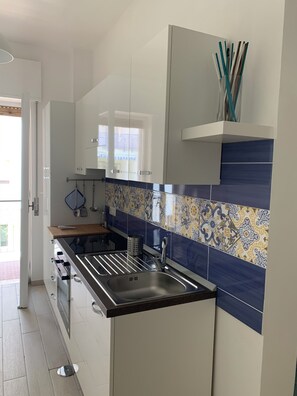 Una cocina moderna con armarios blancos, encimera negra y salpicadero estampado.