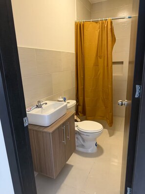 Casa de banho com lavatório branco, sanita e cortina de chuveiro.