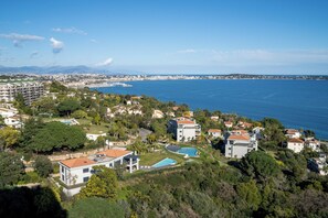 Una zona residencial costera con casas modernas, un hotel grande y una vista despejada del mar.