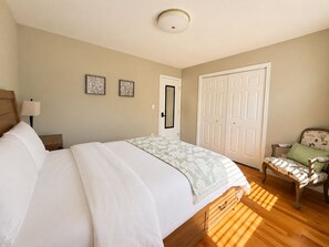 Een slaapkamer met een bed, een stoel, een kledingkast en een deur.
