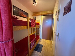 Ein schmaler Flur mit Etagenbetten, einer Tür und einem gerahmten Bild an der Wand.