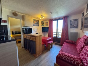 Ein gemütlicher Wohnraum mit Küchenzeile, Essbereich, einer Sitzecke mit Sofa und Fernseher.