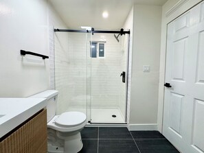 A bathroom with a toilet, a shower enclosure, and a white door. - New Renovated 1B1B Coastal Living Near UCSF & Golden Gate Park (San Francisco)
