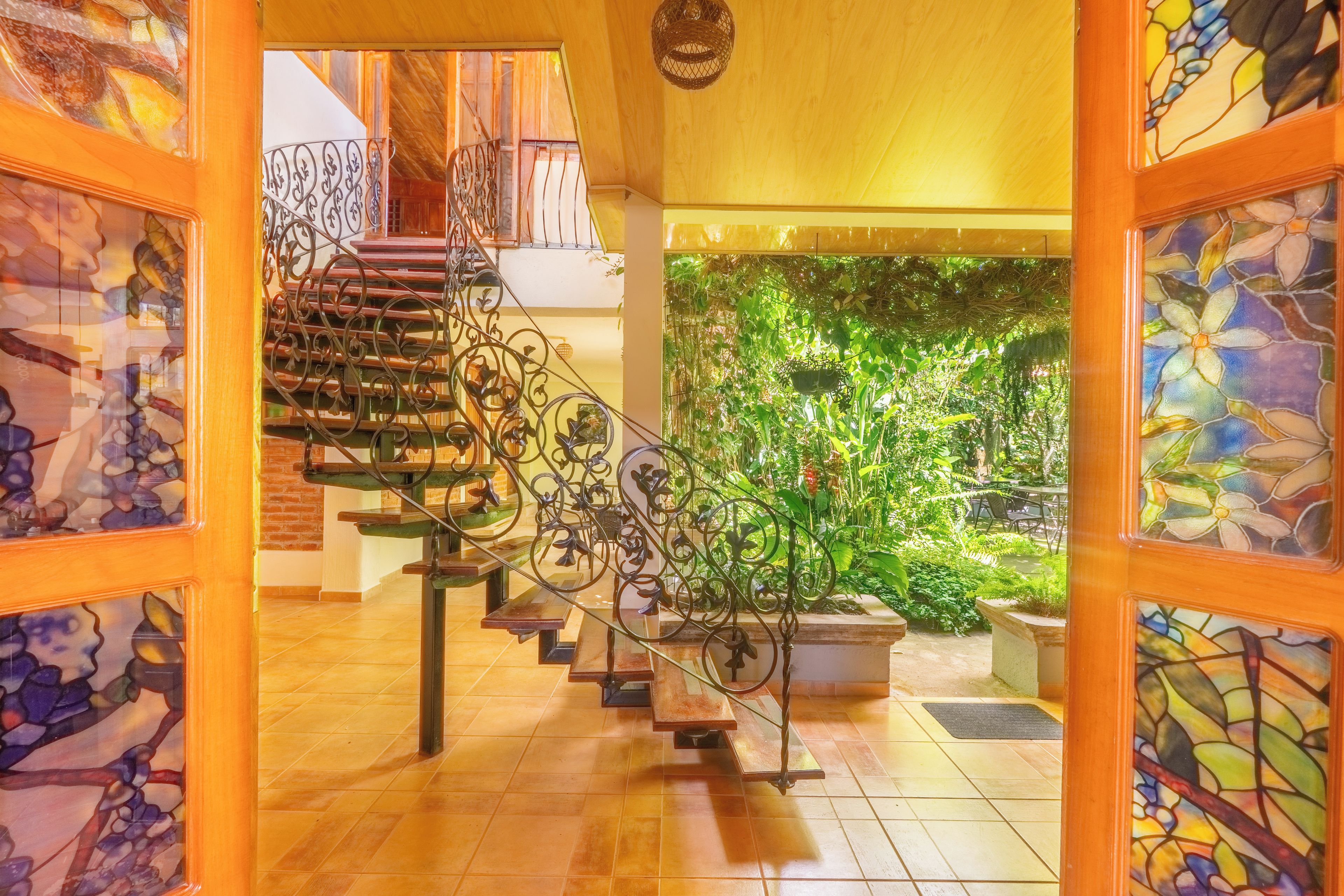Uma escadaria com grades de metal decoradas que leva a um segundo andar.