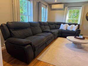 Ein schwarzes, ledernes Modulsofa mit einem weißen Teppich und einem Couchtisch mit einer Pflanze.