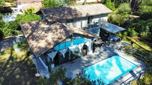 Une maison à deux étages avec une piscine, un patio couvert et un jardin.