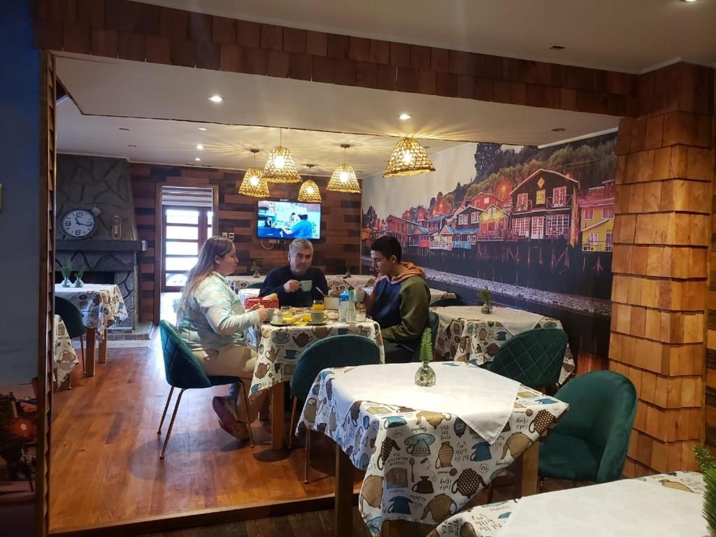 A restaurant with wooden walls, tables with patterned tablecloths, and hanging lights.