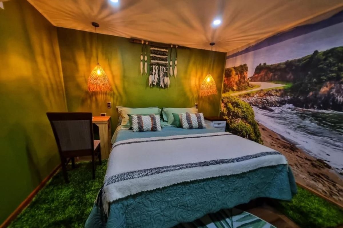 Un dormitorio con una cama, dos lámparas de pared, una silla y un mural de un paisaje costero.