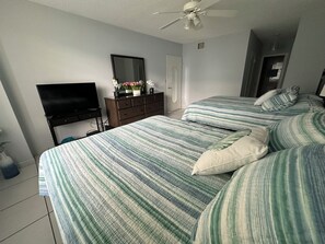 Una camera da letto con un letto, una TV, una cassettiera e una ventola a soffitto.