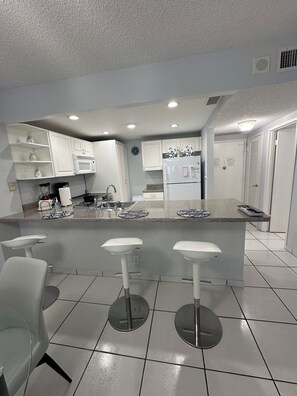 Una cucina moderna con mobili bianchi, un'isola centrale con sgabelli da bar e un forno a microonde.
