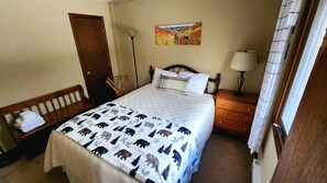 Una camera da letto con un letto, una panca con asciugamani, un comodino con una lampada e un quadro appeso al muro.