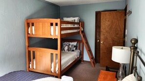 Un letto a castello con struttura in legno, una porta, una lampada e un pavimento rivestito di moquette.