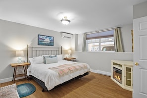A bedroom with a bed, bedside lamps, a painting, a window with curtains, and a fireplace. - Cozy 3-Bedroom, 2-Bath Home with Private Pool & Hot Tub, Chester Front Harbour (Chester)