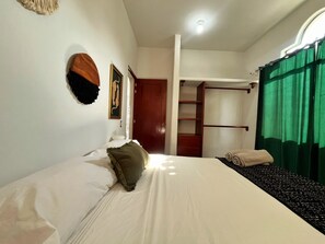 Une chambre à coucher avec un lit, une armoire et un rideau vert.