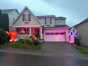 A residential house with a garage door, a porch with Halloween decorations, and a well-maintained lawn. - Enjoyable 1-bedroom house with AC in charming Renton (Renton)