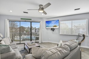 Un salon moderne avec un canapé, une table basse, un téléviseur et un ventilateur de plafond.