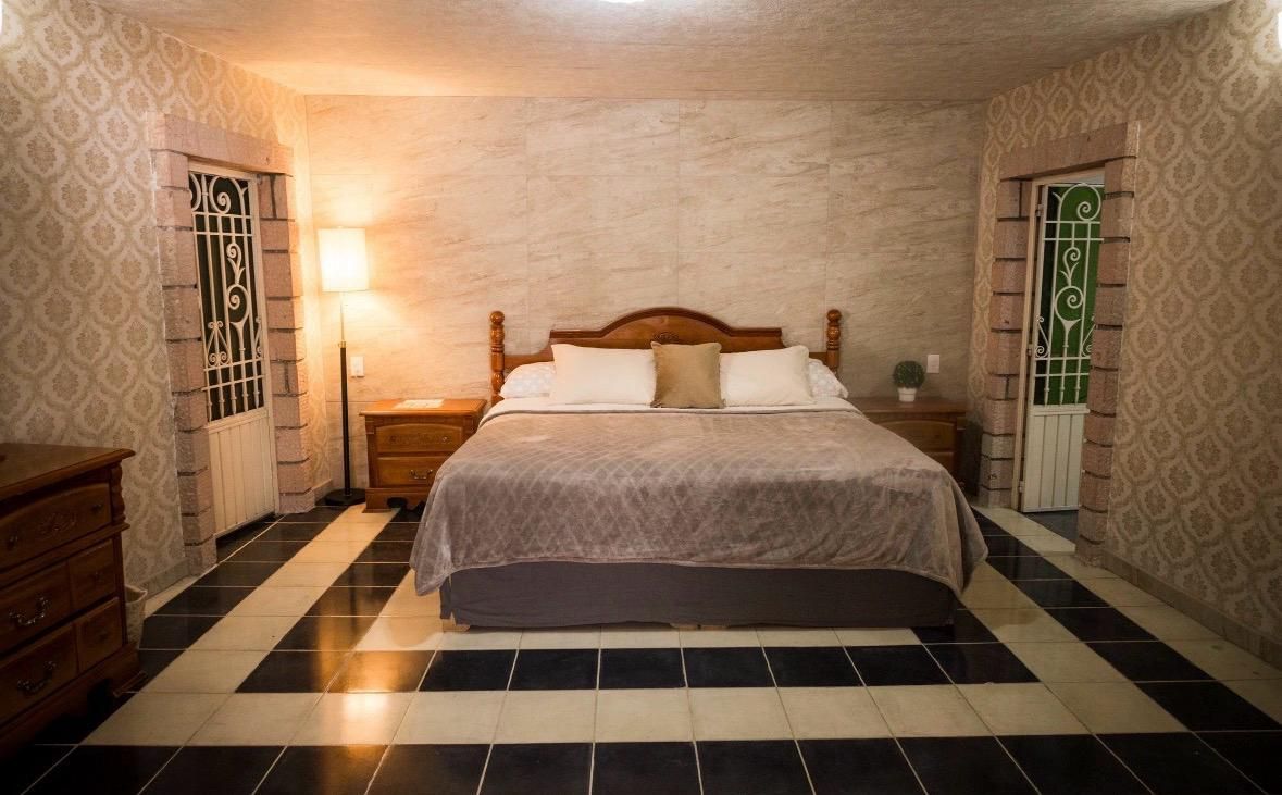 Ein Schlafzimmer mit einem Bett, Nachttischen und Wandverkleidung mit Muster.