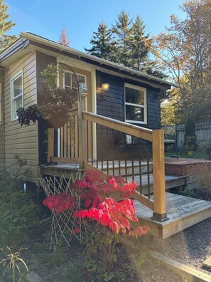 Ein zweistöckiges Haus mit einer Holzterrasse und einer kleinen Veranda.