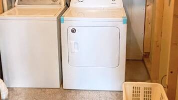 A laundry area with two washing machines and a plastic laundry basket.