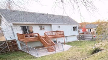 A two-story house with a wooden deck and a staircase leading to a balcony.