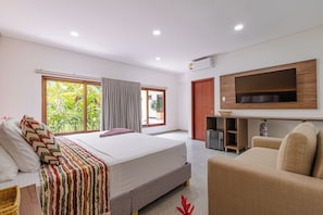 Une chambre d’hôtel moderne dotée d’un grand lit, d’un téléviseur fixé au mur et d’un coin salon avec un canapé et des fauteuils.