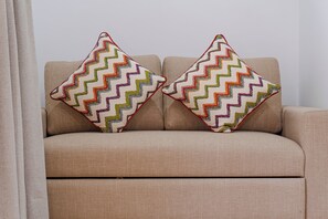 Un sofà beix amb dos coixins decoratius amb dibuixos en zig-zag.