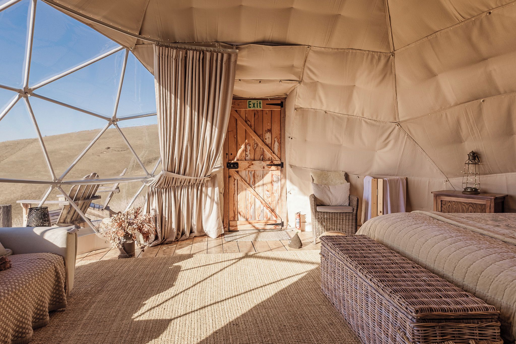 Habitación con carpa, una cama, una silla, una mesita y vista al desierto.