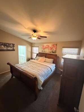 Une chambre à coucher avec un lit en bois, un ventilateur de plafond et une table de chevet.