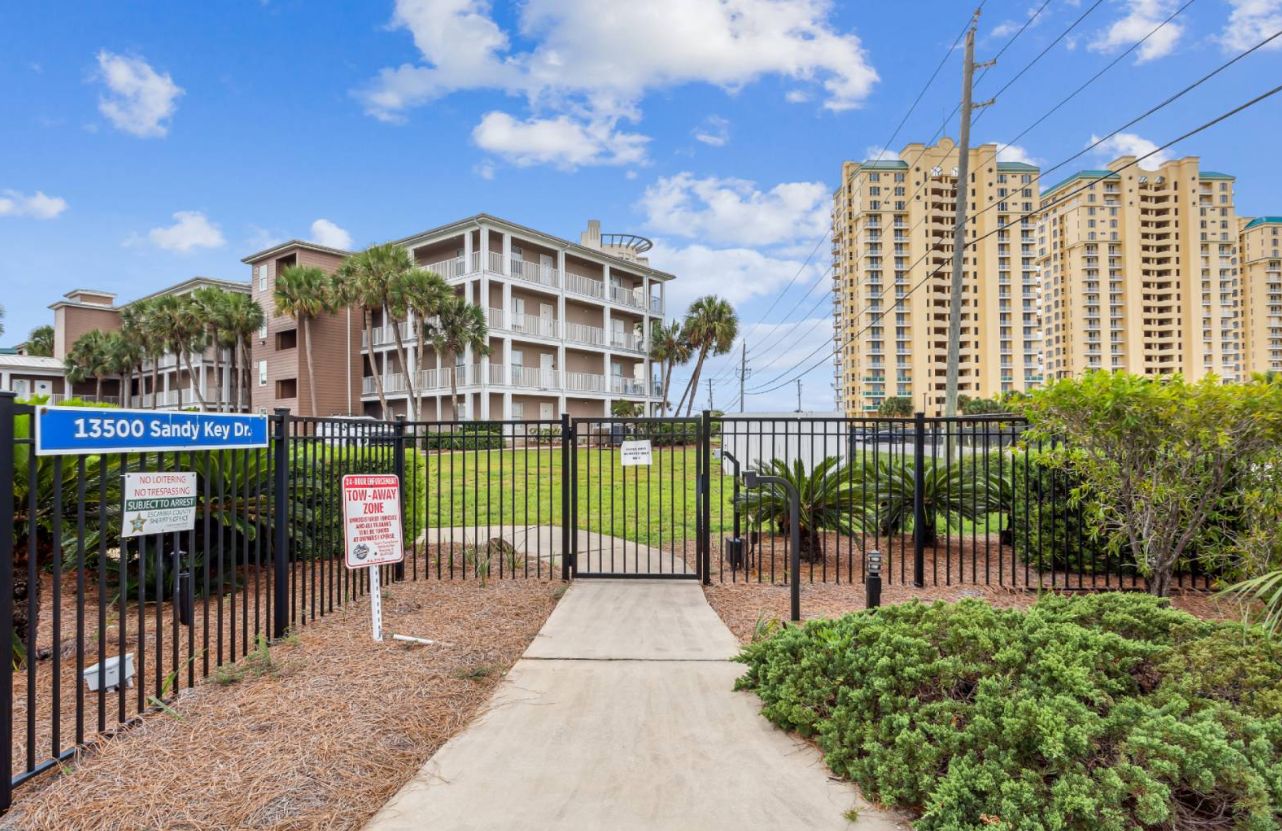 A gated residential area with a building labeled '13500 Sandy Key Dr.' and a 'No Trespassing' sign.